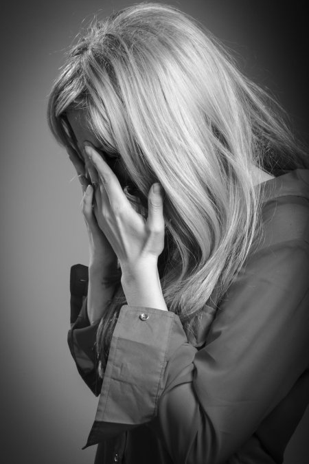 Женщина закрывает лицо руками