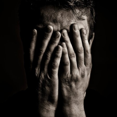 Человек закрывает лицо руками