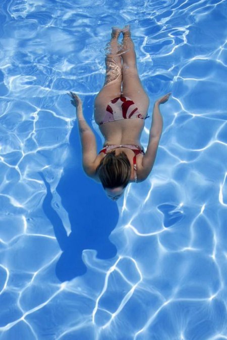 Девушка плывет в бассейне