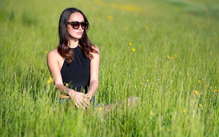 Девушка в очках сидит на природе