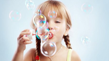 Девочка дует мыльные пузыри