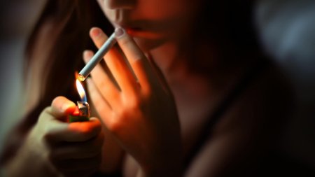 Прикуривает сигарету