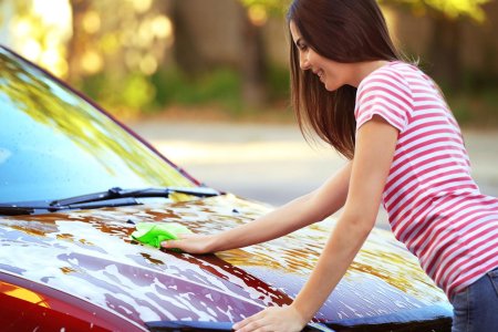 Женщина моет машину