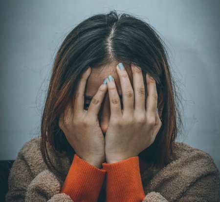Девушка закрывает лицо руками