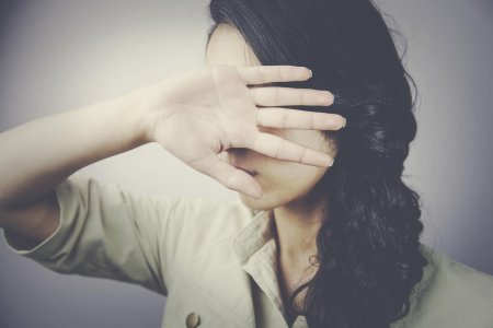 Девушка прикрывает лицо рукой