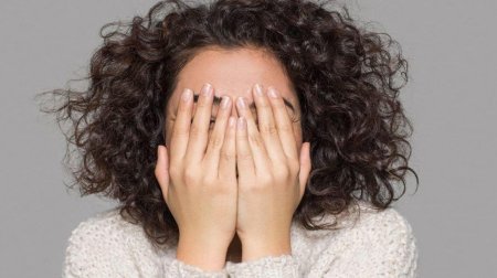 Женщина закрывает лицо руками