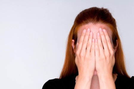 Закрывает лицо руками