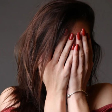 Девушка прикрывает лицо рукой