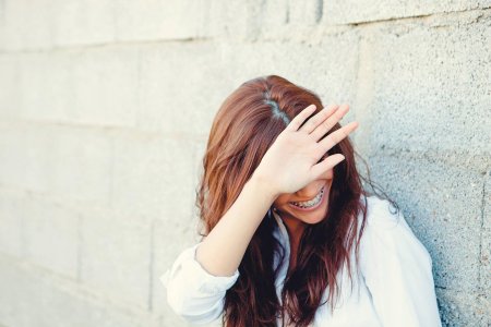 Закрывает лицо руками