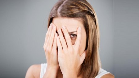 Закрывает лицо руками