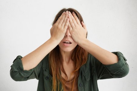 Женщина закрывает лицо руками