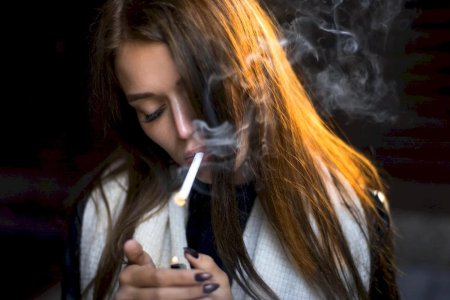 Девушка подкуривает сигарету