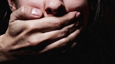 Закрывает рот рукой