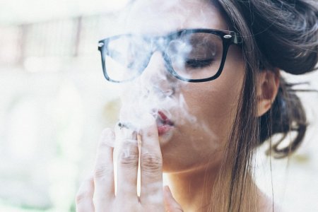 Девушка в очках для зрения с сигаретой
