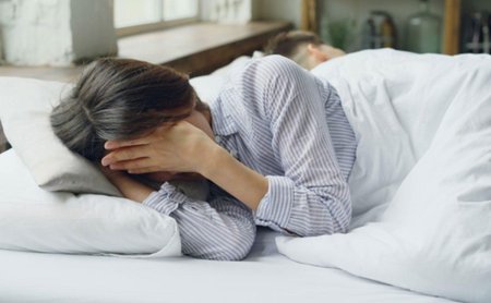 Женщина грустна на кровати