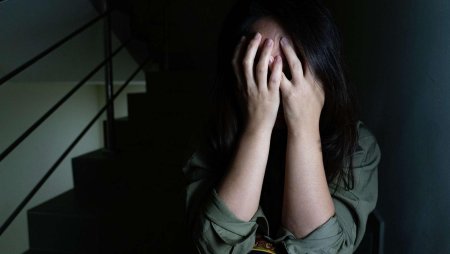 Закрывает лицо руками