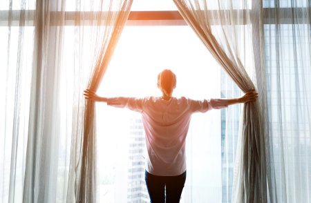 Женщина открывает шторы