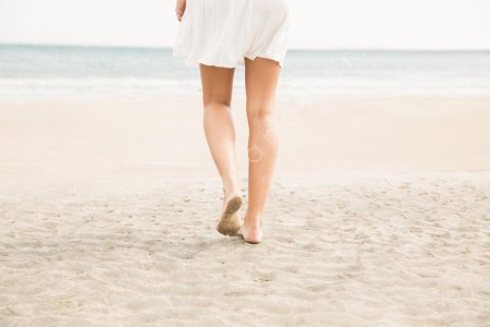 Женские ноги идут по песку