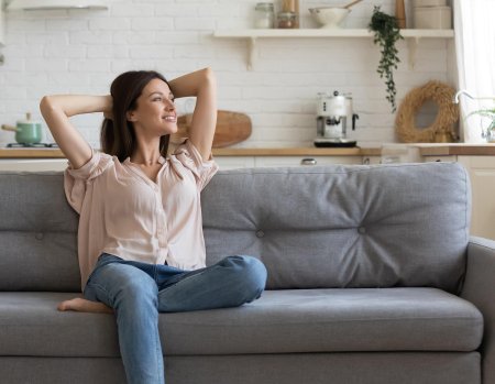 Счастливая женщина дома на диване