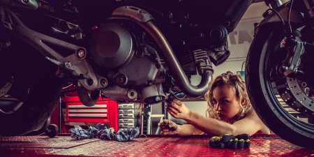 Девушка чинит мотоцикл