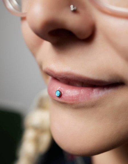 Closeup of a young woman's visage with piercing Hanging from her nose.