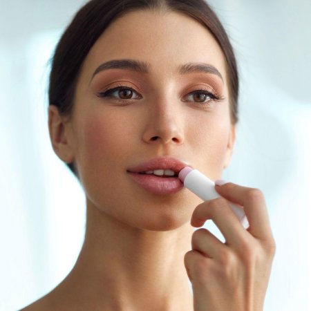 Девушка наносит бальзам на губы