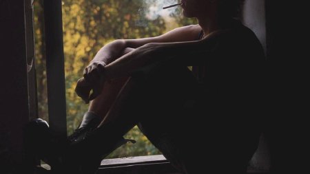 Человек у окна с сигаретой