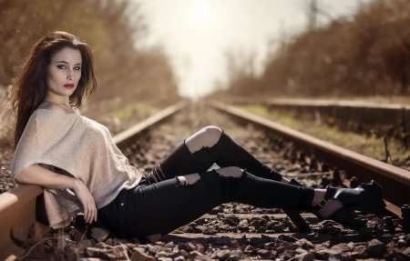 Девушка шатенка стоит на железной дороге