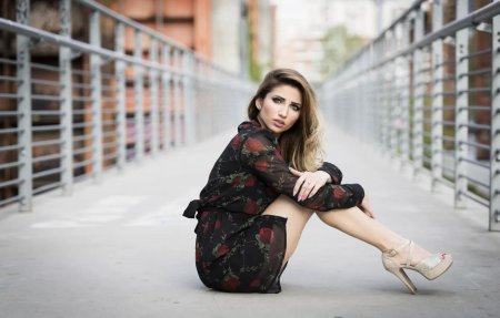 Девушка в платье сидит боком