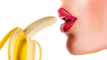 Девушка облизывает банан