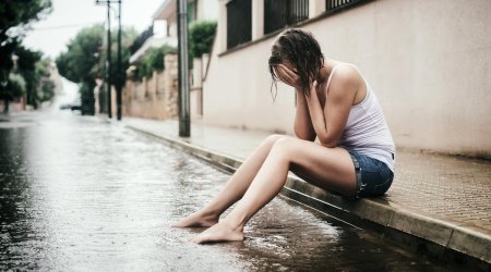 Девушка сидит под дождем