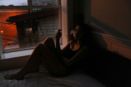 Девушка курит на балконе