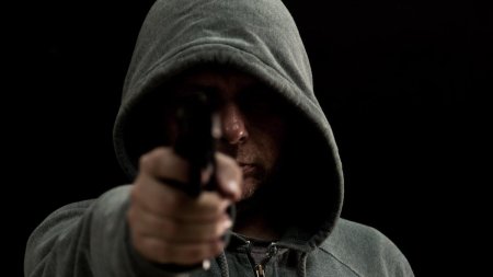 В капюшоне с пистолетом