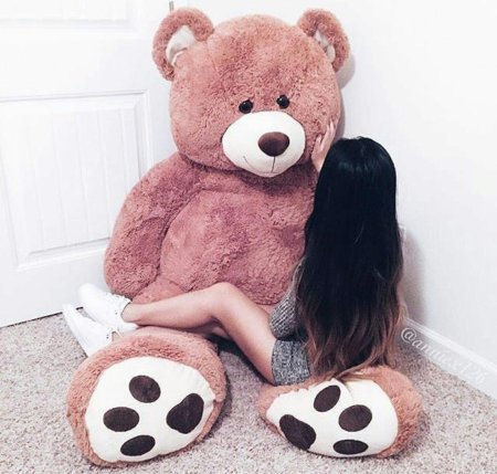 Девушка обнимает плюшевого медведя