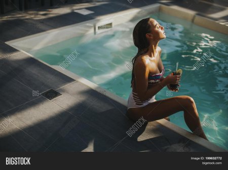 Девушка в бассейне с коктейлем