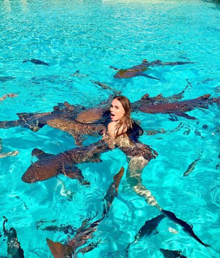 Девушка в бассейне с акулами