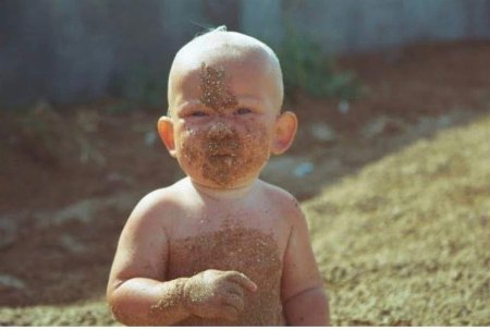 Ребенок ест песок в песочнице