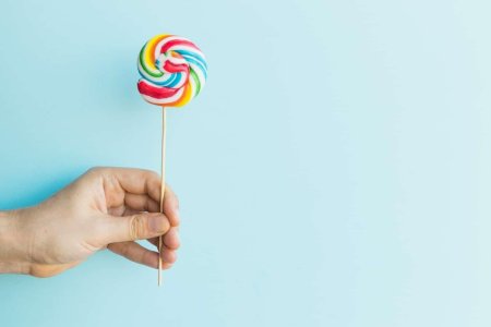 Леденец на палочке в руке