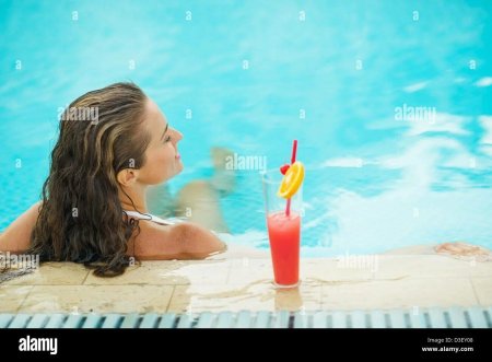 Девушка в бассейне с коктейлем