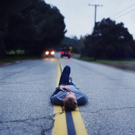Мужчина сидит на дороге