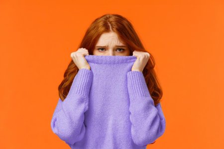 Девушка прячет лицо в свитере