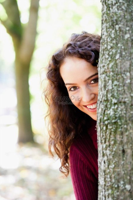 Девушка выглядывает из за дерева